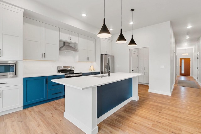 kitchen featuring stainless steel appliances, extractor fan, light wood-style floors, and blue cabinetry