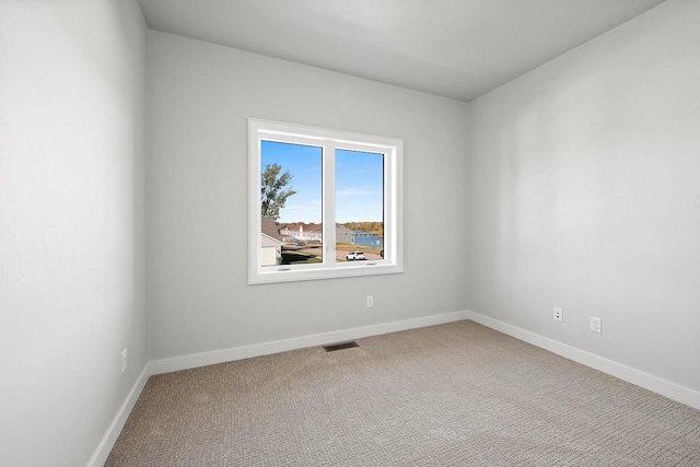 empty room featuring baseboards, visible vents, and carpet