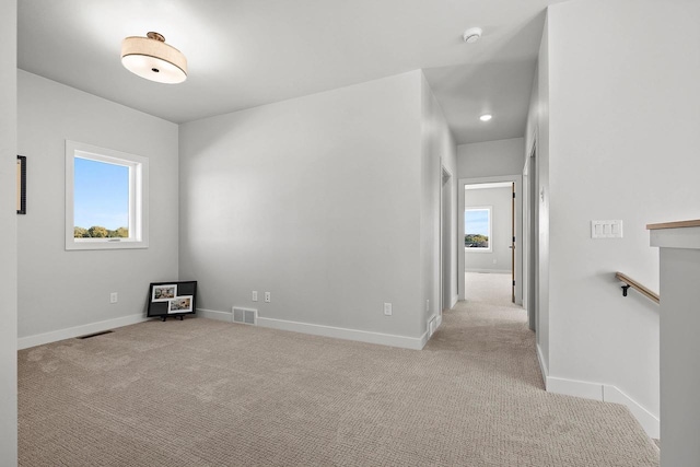 empty room with baseboards, visible vents, and light colored carpet