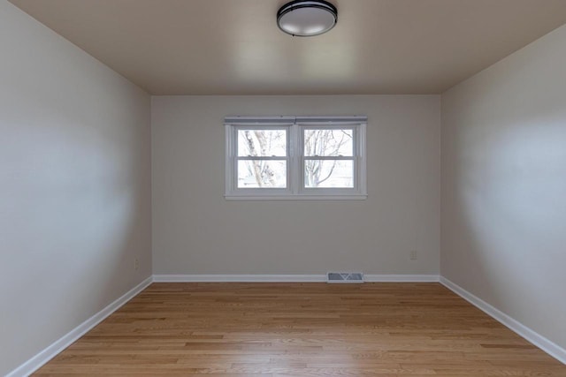 unfurnished room with light wood-type flooring, visible vents, and baseboards