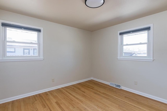 empty room with light wood-type flooring, baseboards, and visible vents