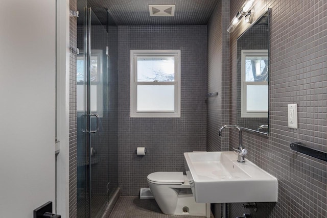 full bathroom featuring a healthy amount of sunlight, tile walls, a sink, and a stall shower