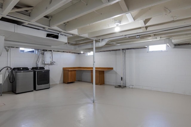 below grade area featuring washing machine and dryer, concrete block wall, and electric panel