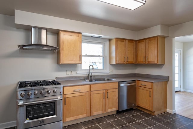 kitchen featuring a sink, baseboards, wall chimney exhaust hood, appliances with stainless steel finishes, and dark tile patterned floors