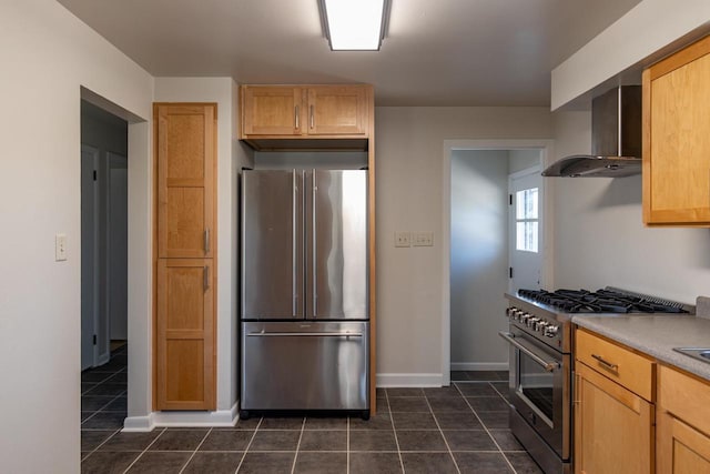 kitchen featuring baseboards, wall chimney exhaust hood, high end appliances, and dark tile patterned flooring