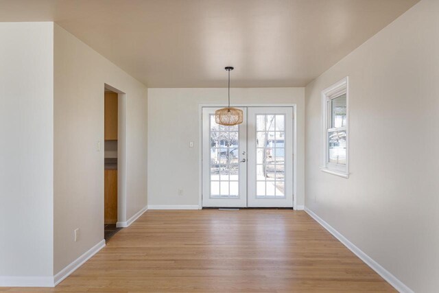 unfurnished dining area with baseboards, french doors, and light wood finished floors