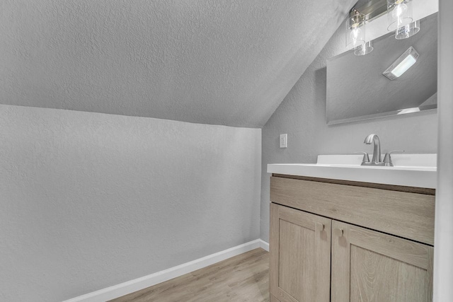 6824 W Hayes Ave, West Allis, WI 53219 - bathroom with wood finished floors, a textured ceiling, a textured wall, baseboards, and lofted ceiling