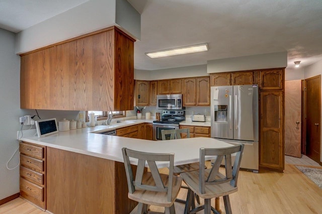 504 Lake St, Mount Horeb, WI 53572 - kitchen featuring stainless steel appliances, brown cabinets, a peninsula, and light wood-type flooring