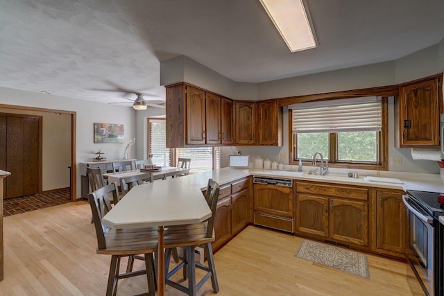 504 Lake St, Mount Horeb, WI 53572 - kitchen featuring dishwasher, a sink, stainless steel range with electric stovetop, light wood finished floors, and brown cabinetry