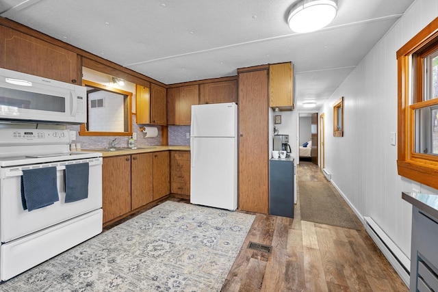 N4823 Peppler Ln, Wild Rose, WI 54984 - kitchen featuring white appliances, light wood-style flooring, a baseboard radiator, brown cabinets, and a sink