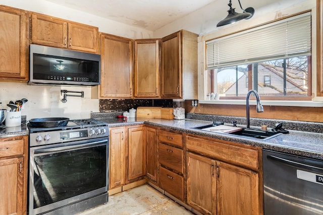 607 Jefferson Ave, Omro, WI 54963 - kitchen featuring dark countertops, a sink, brown cabinetry, backsplash, and appliances with stainless steel finishes