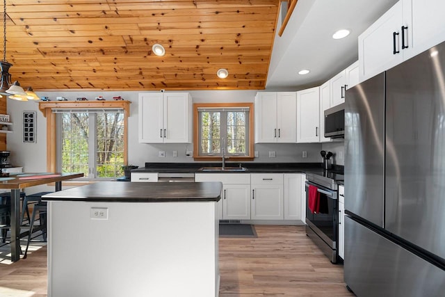 kitchen featuring dark countertops, light wood-style flooring, stainless steel appliances, and a sink