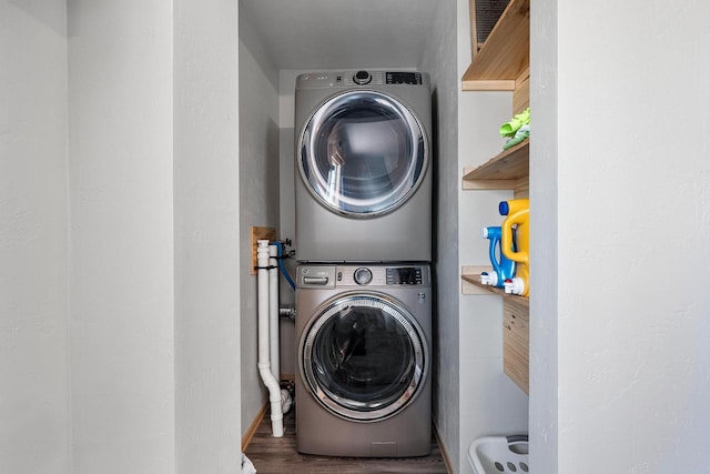 clothes washing area featuring stacked washing maching and dryer, wood finished floors, and laundry area