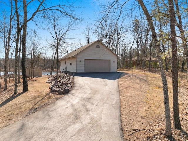 view of property exterior with an outdoor structure and driveway