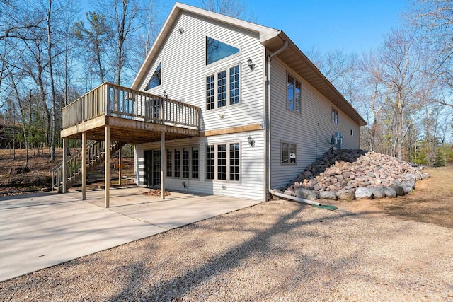 rear view of house with a wooden deck, driveway, stairs, and a patio area