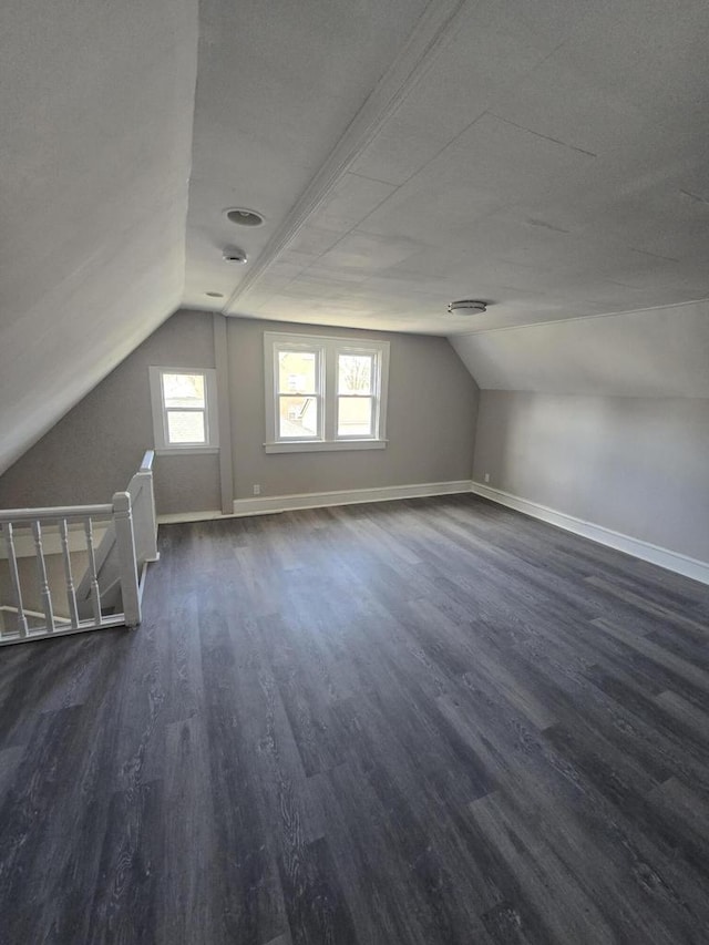 additional living space featuring vaulted ceiling, baseboards, and dark wood-type flooring