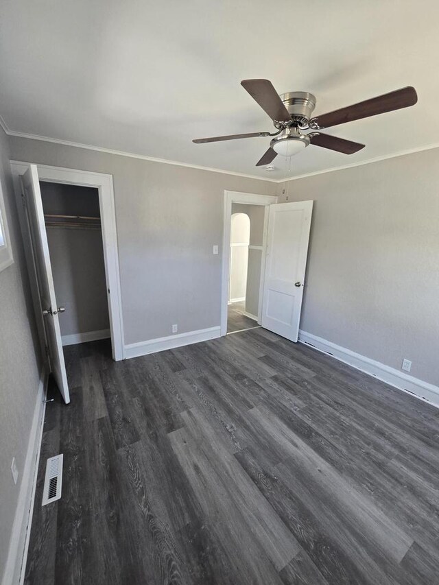 unfurnished bedroom featuring ornamental molding, baseboards, dark wood-style flooring, and visible vents