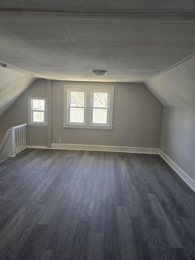 additional living space with dark wood finished floors, lofted ceiling, and baseboards
