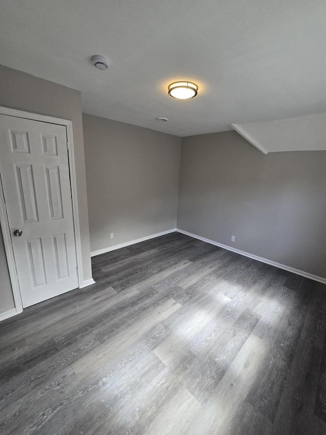 unfurnished bedroom with baseboards and dark wood-type flooring