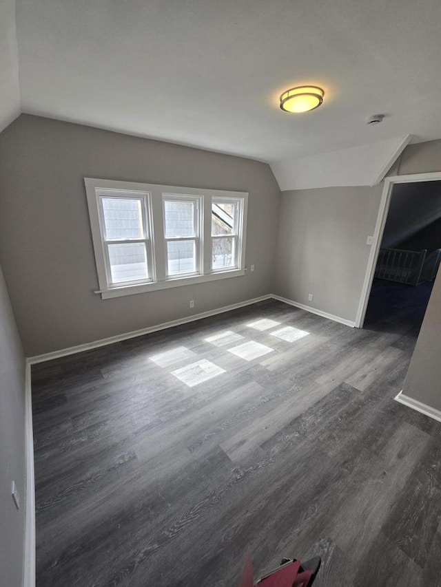 bonus room featuring lofted ceiling, baseboards, and dark wood finished floors