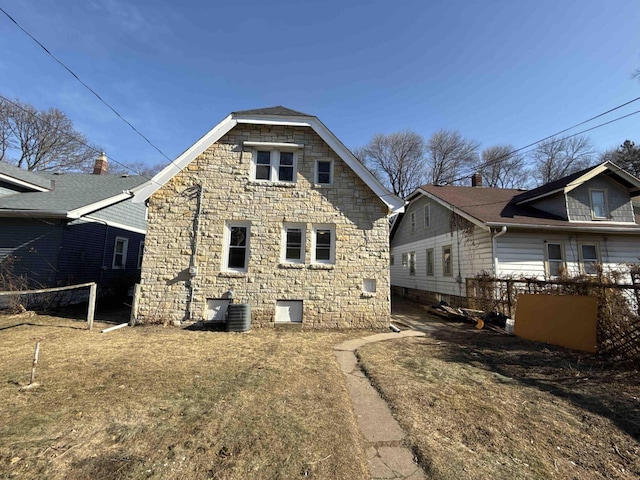 back of property featuring stone siding and fence