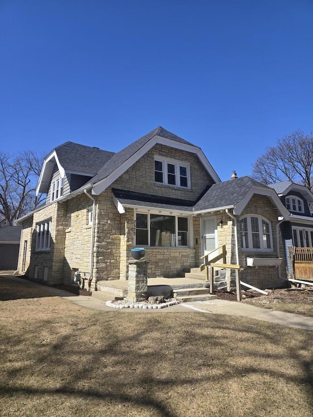 exterior space featuring stone siding and a shingled roof