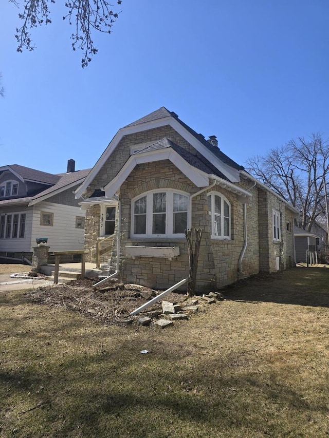back of house with a lawn and stone siding