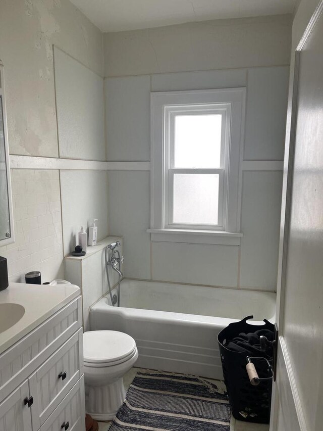 bathroom featuring toilet, vanity, and a tub