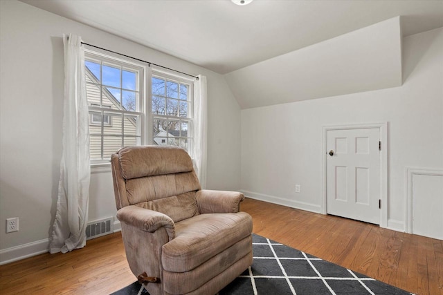 living area with lofted ceiling, baseboards, wood finished floors, and visible vents