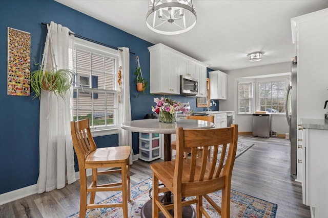 dining area with baseboards, light wood-style floors, and a chandelier