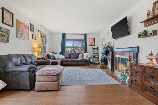 living room featuring a brick fireplace and wood finished floors
