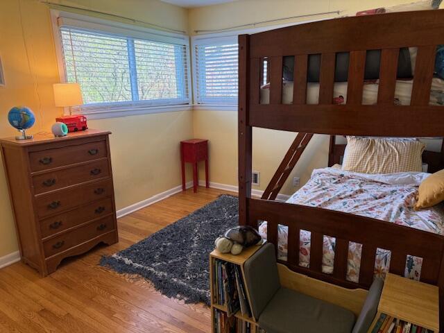 bedroom featuring baseboards, wood finished floors, and multiple windows