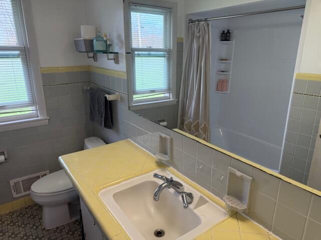 bathroom featuring visible vents, tile patterned floors, toilet, and tile walls