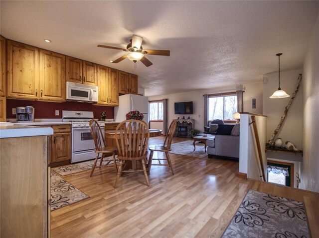 kitchen with light countertops, ceiling fan, light wood-type flooring, and white appliances