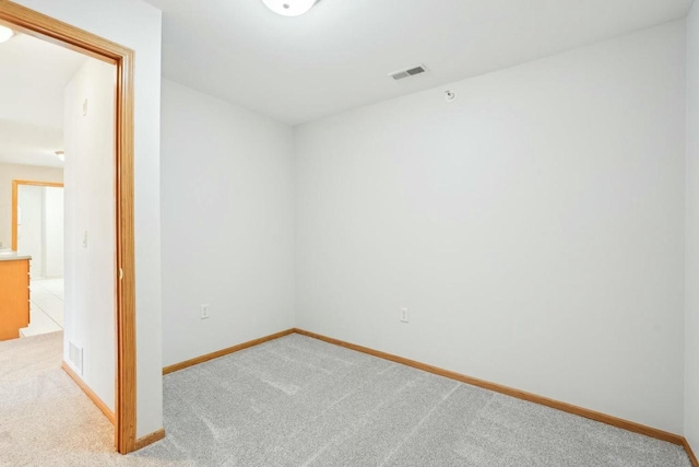 unfurnished room with carpet, visible vents, and baseboards