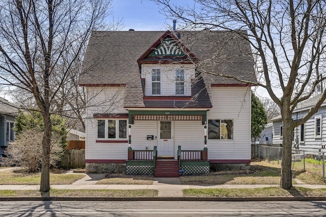 victorian house featuring fence and a shingled roof