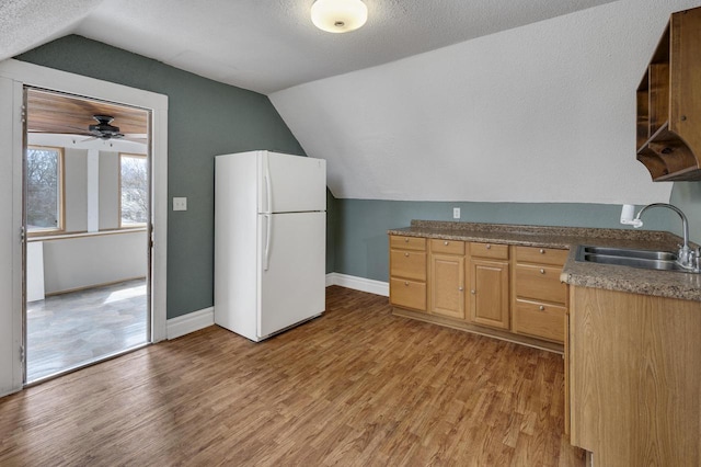 kitchen with freestanding refrigerator, vaulted ceiling, light wood-type flooring, and a sink