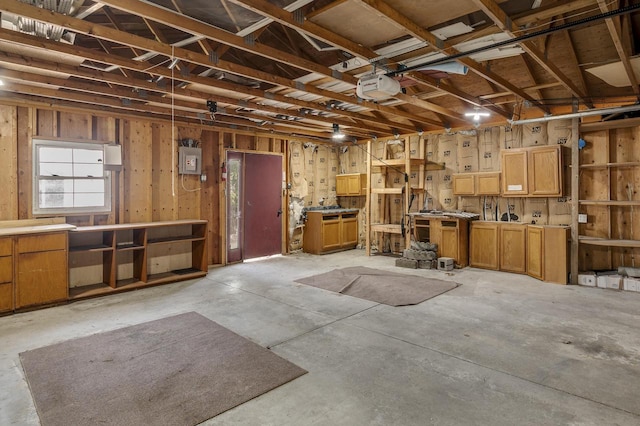 miscellaneous room with a garage, electric panel, a workshop area, and unfinished concrete floors