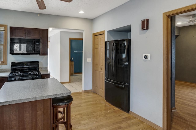 kitchen featuring ceiling fan, baseboards, and black appliances