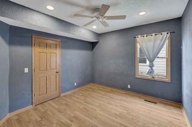 unfurnished room with wood finished floors, visible vents, a ceiling fan, baseboards, and a textured ceiling