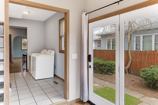 clothes washing area with washing machine and dryer, light tile patterned floors, baseboards, and laundry area