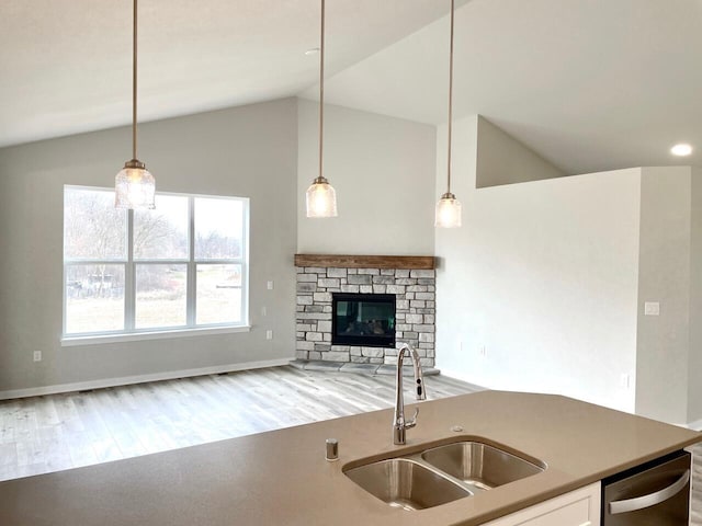 W255S5377 Primrose Ln, Waukesha, WI 53189 - kitchen featuring stainless steel dishwasher, hanging light fixtures, a sink, light wood-style floors, and a fireplace