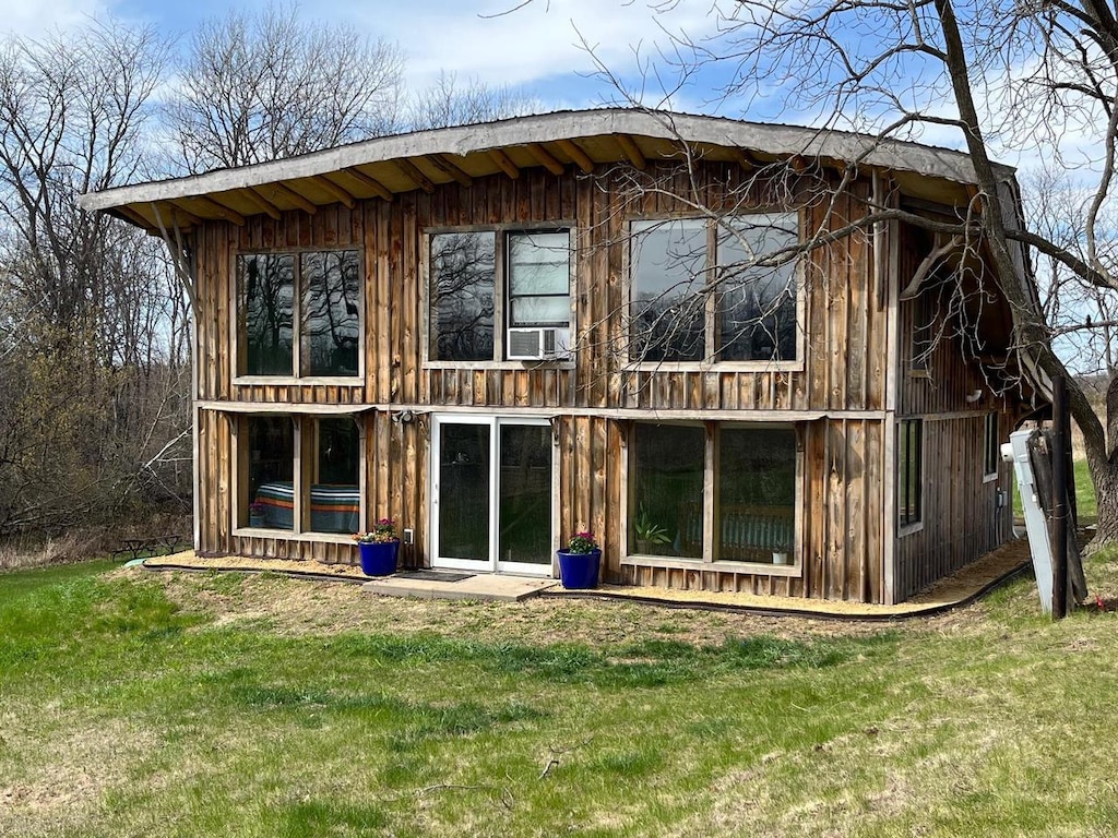 back of house with board and batten siding, a yard, and cooling unit
