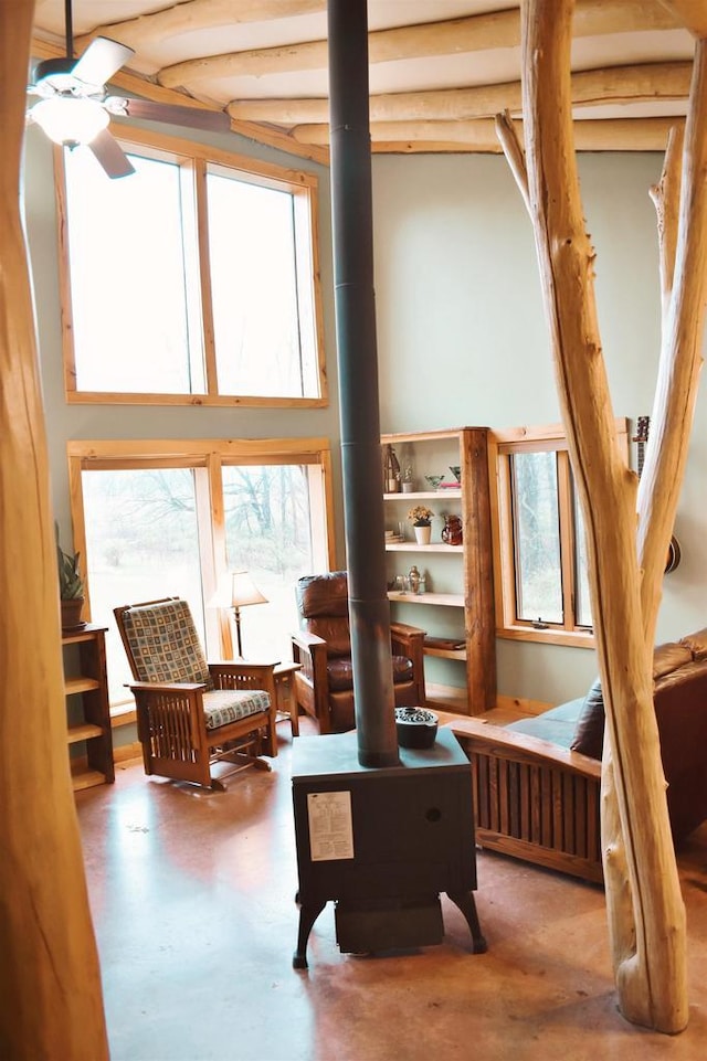 5664 N Dutch Hollow Rd, Potosi, WI 53820 - sitting room with concrete floors, a ceiling fan, a wood stove, and a towering ceiling