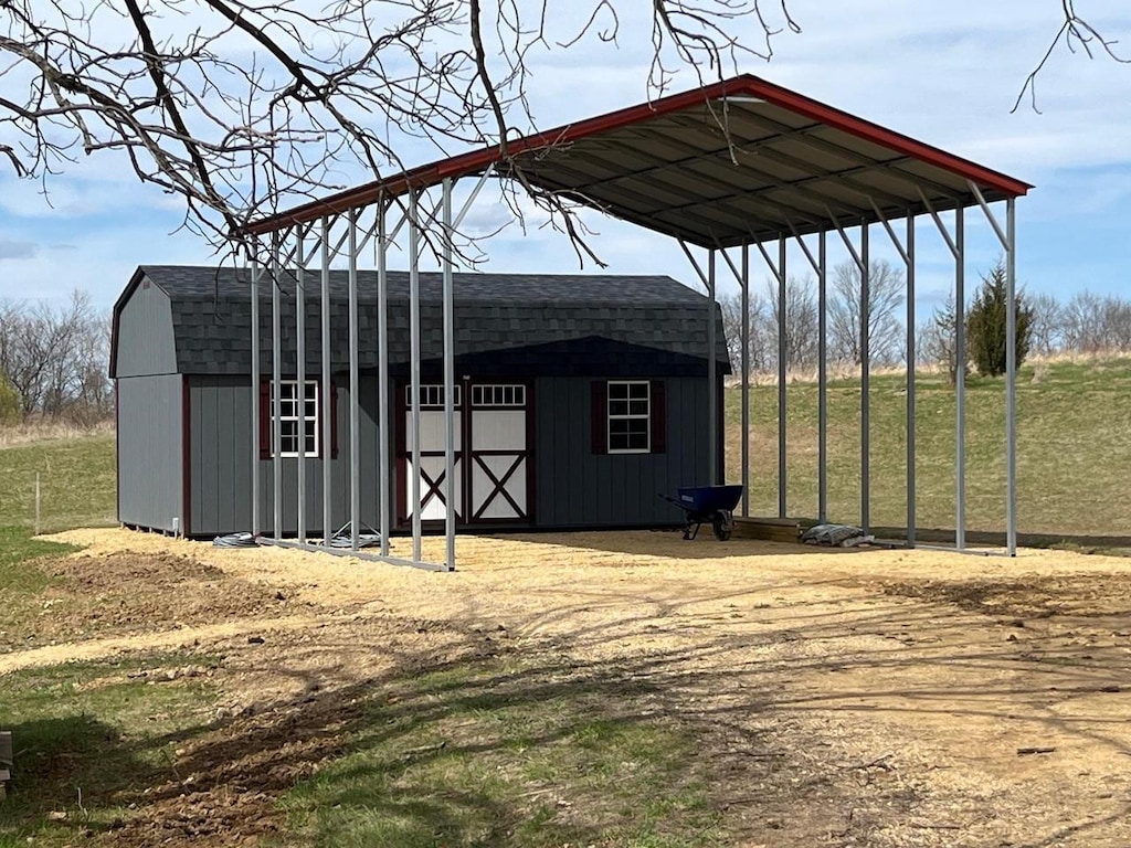 view of outdoor structure with a detached carport, an outbuilding, and driveway