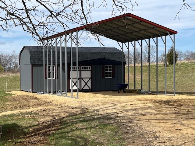 view of outdoor structure with a detached carport, an outbuilding, and driveway
