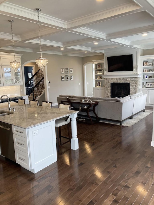 4922 Saint Annes Dr, Waunakee, WI 53597 - kitchen with arched walkways, a kitchen breakfast bar, coffered ceiling, and a stone fireplace