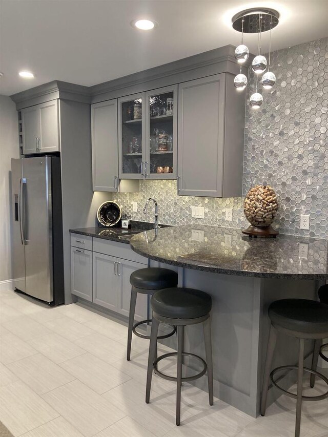 4922 Saint Annes Dr, Waunakee, WI 53597 - kitchen with glass insert cabinets, a kitchen bar, stainless steel fridge with ice dispenser, a sink, and gray cabinetry