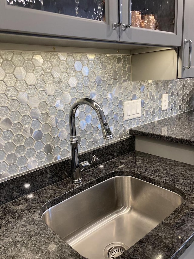 4922 Saint Annes Dr, Waunakee, WI 53597 - room details featuring a sink, dark stone counters, backsplash, and glass insert cabinets
