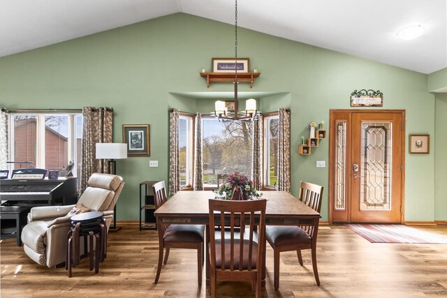 dining area featuring baseboards, high vaulted ceiling, a chandelier, and wood finished floors